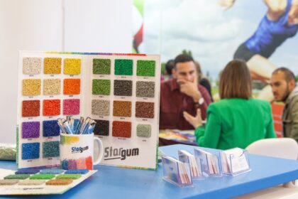 Próbki kolorowych granulek na stoisku z rozmową trzech osób w tle