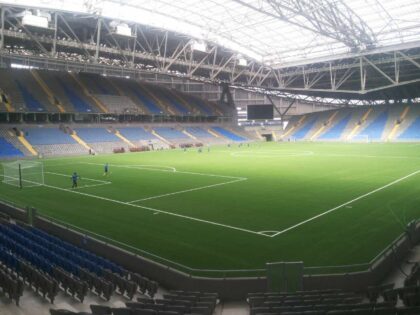 Pusty stadion piłkarski z kilkoma zawodnikami trenującymi na boisku