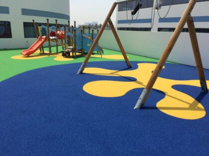 Kolorowy plac zabaw z zjeżdżalnią, huśtawką i bezpieczną, gumową nawierzchnią