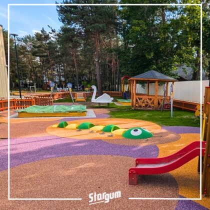 Kolorowy plac zabaw w lesie z zjeżdżalnią, huśtawką i altaną